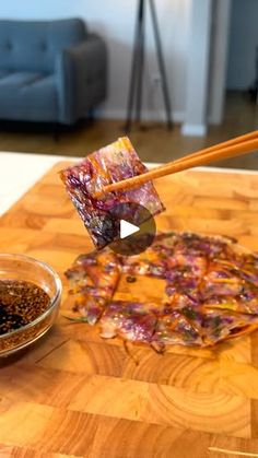 chopsticks are being used to stir food on a wooden table in a living room