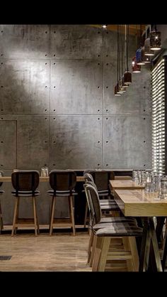 an empty restaurant with wooden tables and chairs in front of a wall that has metal panels on it