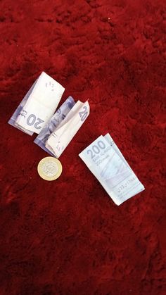 two pieces of paper money laying on a red carpet