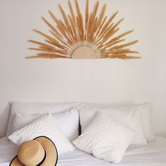 a hat on top of a bed next to pillows and a wall hanging above it