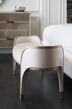 a white chair sitting on top of a wooden floor next to a dresser and mirror