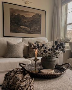 a living room with a couch, coffee table and vase filled with flowers on it