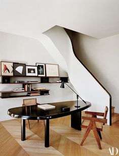 a room with a table, bookshelf and pictures on the wall above it