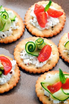 crackers with cucumbers, tomatoes and cheese on them are arranged in a circle