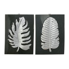 two metal leaf wall hangings on black and white tile, one with silver leaves