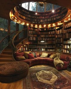 a living room filled with lots of books on top of a wooden floor next to a spiral staircase