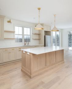 a large kitchen with an island and two pendant lights hanging from it's ceiling