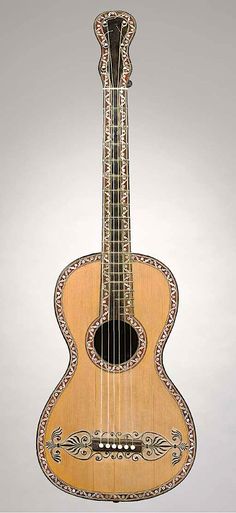 a small wooden guitar with intricate designs on it's back and sides, sitting against a white background