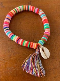 multicolored beaded bracelet with seashell and tassel on wooden table top