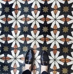 a person wearing black shoes standing in front of a tiled floor with stars on it