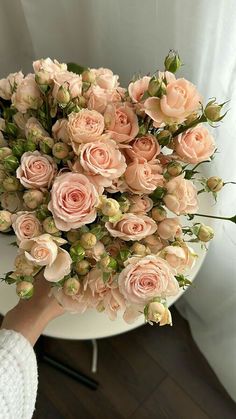 a person holding a bouquet of flowers on top of a table