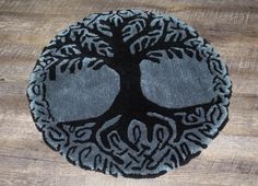 a black and gray tree of life rug on a wooden floor with wood planks