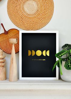 a white shelf topped with vases and plants next to a black framed wall art