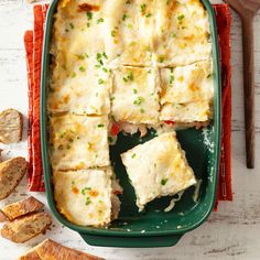 a green casserole dish filled with meat and cheeses next to bread slices