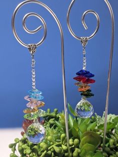 the earrings are made from glass beads and silver wire with spiral designs on them, along with small green plants