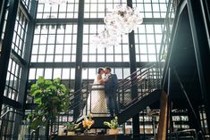 a bride and groom are standing on the stairs in an old building with lots of windows