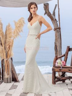 a woman in a wedding dress standing on the beach