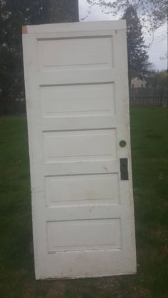 a white door sitting in the grass next to a tree