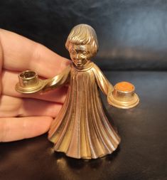 a small gold figurine holding a candle holder