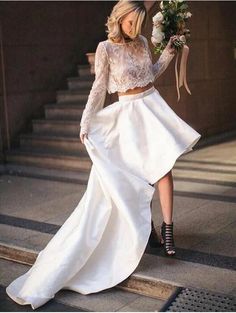 the woman is walking down the stairs with her bouquet in hand and wearing a long white skirt