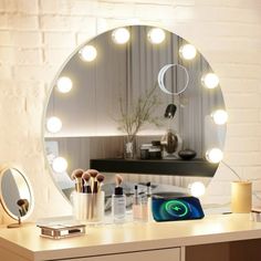 a vanity mirror with lights on it in front of a white brick wall and desk