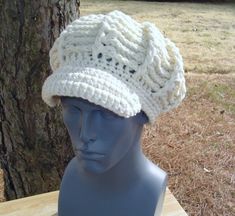 a mannequin head wearing a white crocheted hat on top of a wooden table