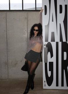 a woman posing in front of a sign that says party girl with her hand on the wall