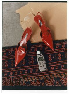 a pair of red high heeled shoes next to a remote control