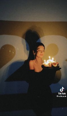 a woman holding a cake with lit candles