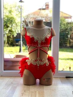 a mannequin wearing a red and gold costume in front of a glass window