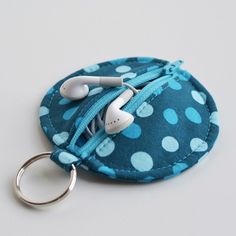 a blue polka dot coin purse keychain with two white earphones on it