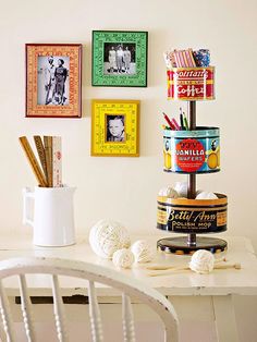 there are many pictures on the wall above this desk and in front of it is a cup with pencils