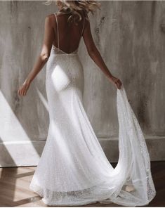 a woman in a white wedding dress is standing on the floor with her back to the camera