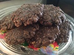 three chocolate cookies stacked on top of each other in a glass dish with a colorful napkin