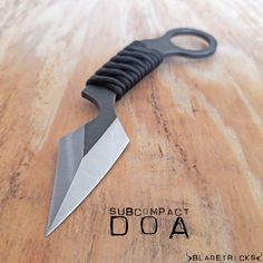 a knife that is sitting on top of a wooden table with the words subcompacct doa underneath it