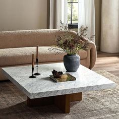 a living room with a couch, coffee table and vase filled with flowers on it