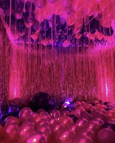 balloons and streamers hanging from the ceiling in a room with purple lights on it