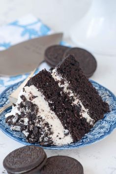 a slice of oreo cake on a blue plate with an oreo cookie next to it