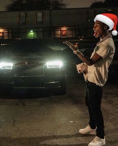 a man standing in front of a car wearing a santa hat