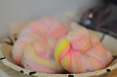 two balls of pink and yellow colored yarn in a bowl on top of a table