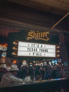 people are sitting at a bar in front of a sign that says, it's a texas thang y'all