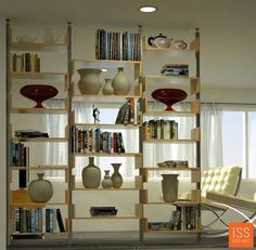 there are many vases and books on the shelves in this living room with white walls