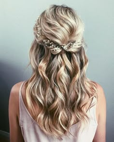 a woman with long blonde hair wearing a flowered headpiece in her left hand