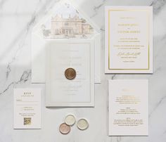 the wedding stationery is laid out on top of the marble countertop, with two coins