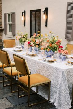 a table set up with plates and vases on it for a formal dinner party