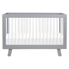 a gray crib with white sheets on it