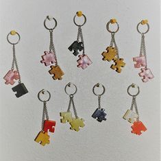 six key chains with different colored puzzle pieces hanging from each one's sides on a white surface