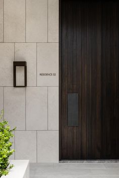 the entrance to a building with a wooden door and planter on the side walk