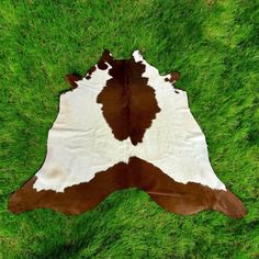 a brown and white cowhide rug on green grass