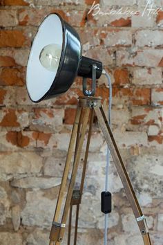 an old fashioned camera on a tripod in front of a brick wall with a spotlight